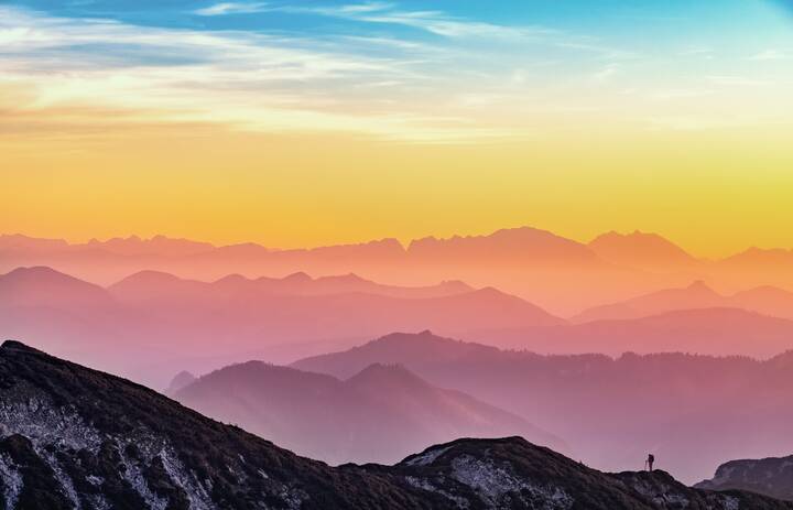 Relaxed view of some mountains with a tiny hiker visible in the foreground